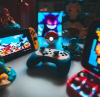 Retrospelskonsoler, handkontroll och spelprylar på ett belyst bord