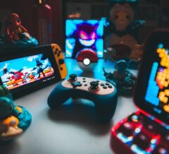 Retrospelskonsoler, handkontroll och spelprylar på ett belyst bord