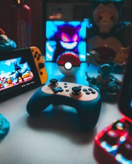 Retrospelskonsoler, handkontroll och spelprylar på ett belyst bord