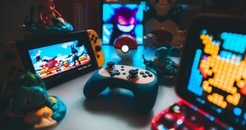 Retrospelskonsoler, handkontroll och spelprylar på ett belyst bord