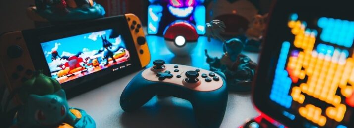 Retrospelskonsoler, handkontroll och spelprylar på ett belyst bord